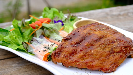 BBQ pork rib with vegetable salad roll on plate.