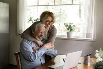 Overjoyed mature couple spouses look at laptop screen triumph read good news online on gadget....