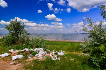 Pollution of nature, a pile of plastic garbage on the shore of a reservoir, ecological disaster,...