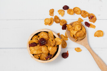 The wooden bowl of caramel cornflakes with raisins on white background for healthy eating and...