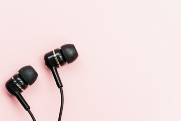 Black earphones on pink background for audio listening concept