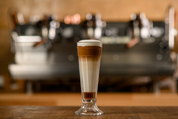 tall glass with delicious drink made of coffee and cream and syrup on table.