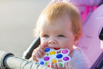 A child sits in a pram with a bright toy in his hands.