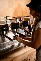 Female barista preparing deliciouse fresh hot coffee drink using professional espresso machine