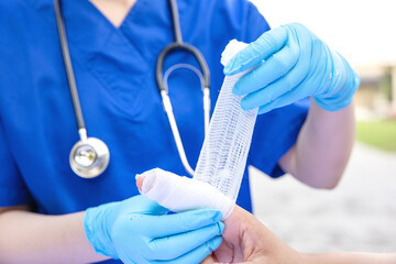 Close-up of female doctor putting a bandage on injured hand upper limb of patient.