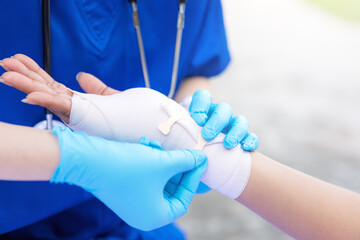 Close-up of female doctor putting a bandage on injured hand upper limb of patient.