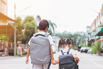 Portrait image of little cute Asian children sibings wearing a face mask and take a school bag....