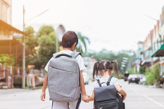 Portrait image of little cute Asian children sibings wearing a face mask and take a school bag. Back to school and kids. Childhood