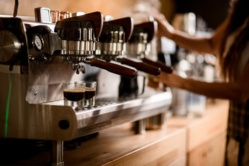 Two glasses with espresso stands on the grating of modern coffee machine