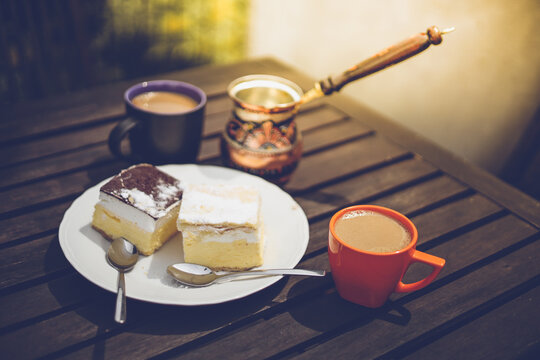 Rustic breakfast. Wooden coffee table with coffee cups, cezve, lake Bled cream cake