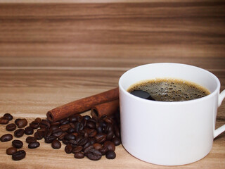Aroma coffee cup and coffee beans with cinnamon on a wooden background. 