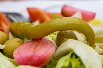 Close-up of a Mediterranean-style salad, made with lettuce, olives, onion and chilli. 