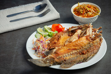 Fried snapper in a plate placed on a black background