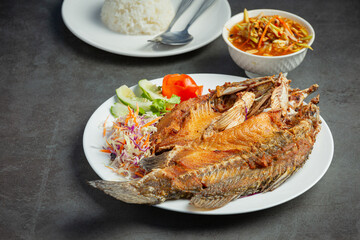 Fried snapper in a plate placed on a black background