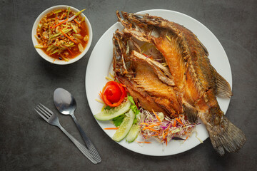 Fried snapper in a plate placed on a black background