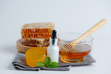 Natural skin care soap and serum with honey and honeycomb laid on white background.
