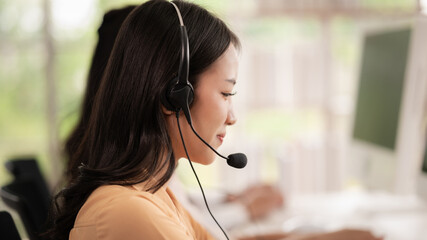 Team of call center staff in Asia wears headphones with a microphone. Smile while serving customers...