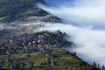 Natural scene Landscape Little village with many fog and Misty around mountain and village with shining sunrise at cemero lawang of Bromo Mountain , Indonesia - Beautiful unseen nature park and travel