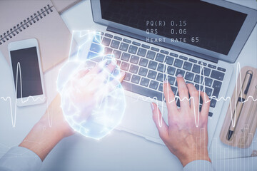 Double exposure of woman hands working on computer and heart hologram drawing. Top View. Medical Science concept.