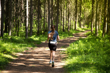 A woman runs in the woods . Fitness classes in the forest.