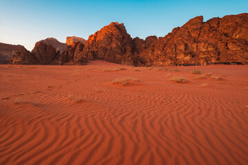 tent camp by the rocks on sunset in the red desert of Wadi Rum in Jordan with patterns on the sand