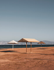 empty beach with umbrellas in the style of minimalism, on the red sea  in Jordan Aqaba, south beach.