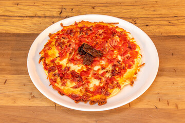 Rare pizza with pieces of ham, pieces of onion, pieces of tomato