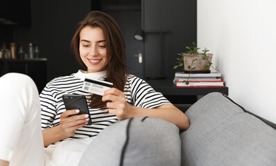 Portrait of resting girl paying on mobile phone for shopping online, holding credit card and...