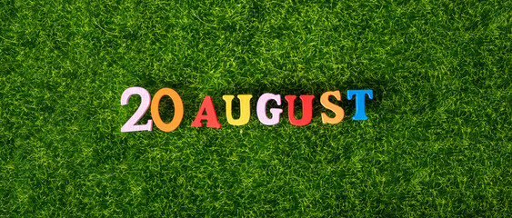 August 20. Image of wooden colored letters and numbers on August 20 against the background of a green lawn.