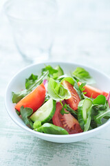 Simple Salad with Tomatoes, Cucumber and fresh Basil. Bright wooden background. Close up. 