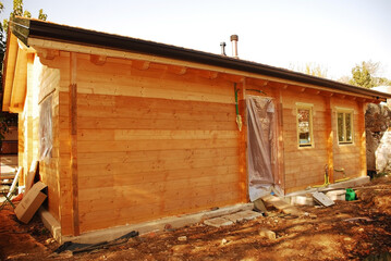 A newly constructed but incomplete wooden (fir) prefabricated house with rain guttering and fitted...