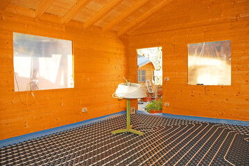 A hydronic closed loop underfloor heating system laid out on a molded insulated panel in EPS with a spooling table inside a partially constructed wooden house. In Udine Province, Friuli-Venezia Giulia