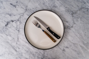 cutlery etiquette in a restaurant consisting of an arrangement of a knife, fork, and plate - obrazy, fototapety, plakaty