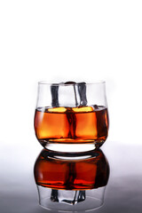 glasses of whiskey with ice cubes on black glass surface