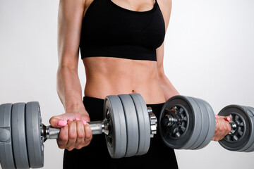 Fototapeta na wymiar A young woman holds dumbbells in her hands. Sports concept