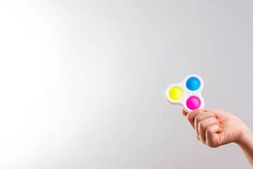 Girl's hands are holding a rainbow pop it fidget toy. Push bubble fidget sensory toy - washable and reusable silicon stress relief popit. A little girl plays with an anti-stress toy takes it out