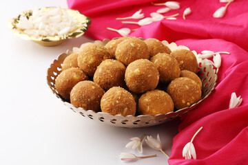 Rava Laddu or Semolina Laddoo Or Rawa Ladu, a popular sweet dish from Maharashtra, India, arranged in a plate with flowers aside
