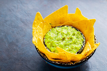 Traditional mexican sauce guacamole with tortilla chips in clay bowl. Bowl of guacamole with nachos...