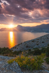 Fototapeta na wymiar Sudak, Crimea - a view from Cape Meganom. Sunset sky with beautiful clouds. The Black Sea and the ridge of the Crimean mountains in the rays of the evening sun.