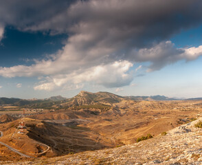 Sudak, Crimea - a view from Cape Meganom. A ridge of the Crimean mountains against the background of a blue sky with beautiful clouds.