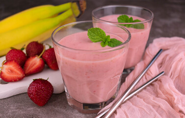 Fresh strawberry banana smoothie in glasses on a gray background.
