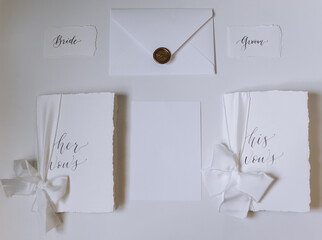 A lot of paper envelopes and invitations with a wax seal lie on a white table. Wedding details and...