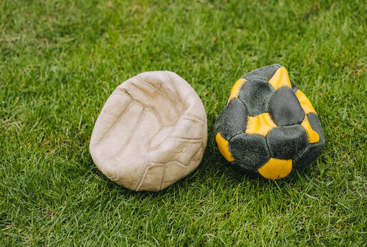 Two deflated old football balls lie on the green grass of the sports field. Photo of a lost match.