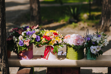 Beautiful, multi-colored, various flowers are in nature in paper boxes, homemade baskets. Wedding photography. Gift for the birthday girl.