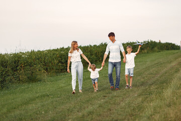 Naklejka na ściany i meble Family walks in a field and playing with toy plane