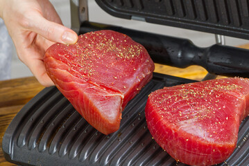 raw tuna steaks cooking on electric grill. Cooking meal at home diet sea food