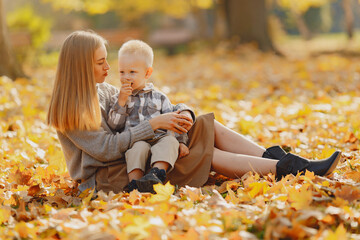Mother with little son sitting in a autumn field