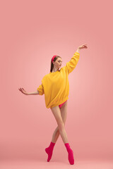 Slim tender young beautiful girl, female ballet dancer dancing isolated over pink background.