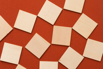 laser cut thin untreated or natural plywood squares on red brown or terracotta fabric background - photographed from above in a flat lay style, with ambient light - sun set color palette