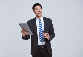 Handsome and friendly face asian businessman smile in formal suit his using tablet on white...